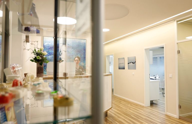 Praxiseingang Heller Innenraum mit Empfangstresen und Flur zu weiteren Räumen.